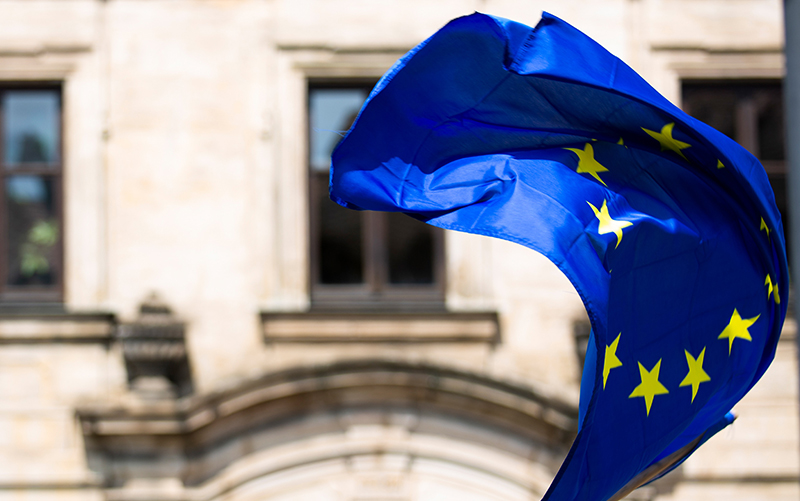 An EU flag flies in front of a building
