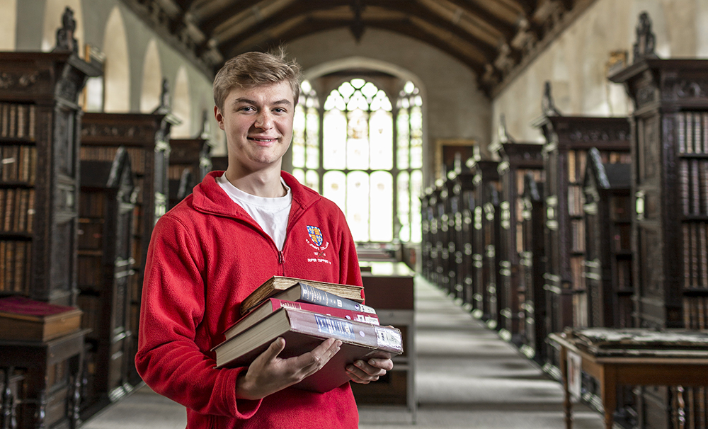 A student holds books and stands in the Old Library