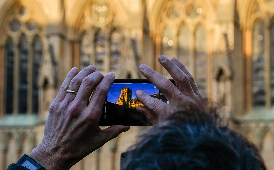 A visitor takes a photo of the College Chapel on his phone