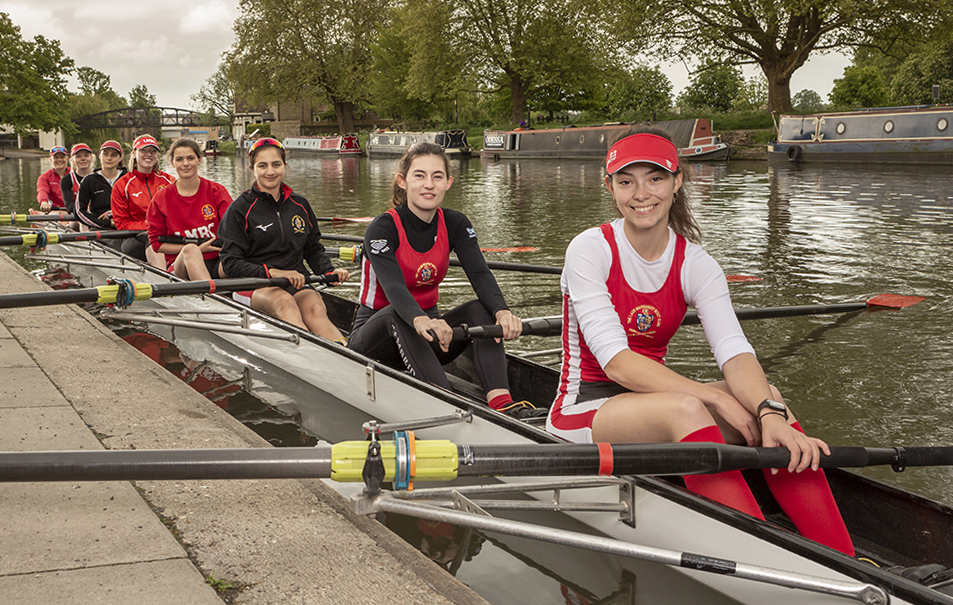 Rowers sit in a boat on the river Cam